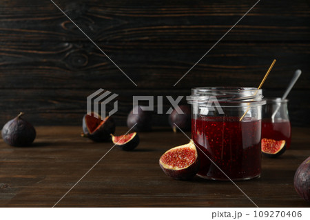 Figs and jars of jam on wooden background, space for text 109270406