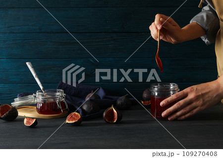 Figs, jars of jam, toweland hands on blue wooden background, space for text Figs, jars of jam, toweland hands on blue wooden background, space for text 109270408