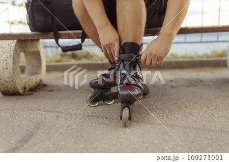 Legs of young man putting on roller skates in the park Legs of young man putting on roller skates in the park 109273001