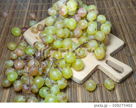 Grapes on the table. Kishmish on a wooden surface. Grapes of different colors on a kitchen board. Wine ingredient. 109273402