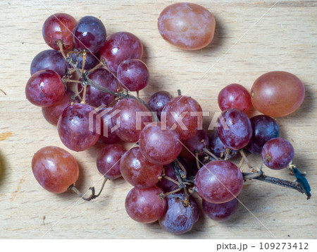 Red variety of grapes on the table. Berry harvest. Home furnishings. Kishmish on the table. Grapes of different colors. Fruit dessert. Wine ingredient. 109273412