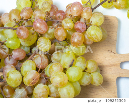 Grapes on the table. White background. Kishmish on a white background. Grapes of different colors on a kitchen board. Wine ingredient. 109273506
