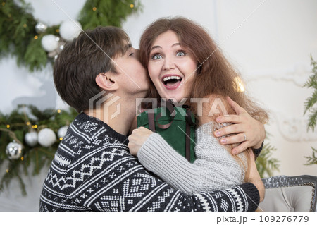 A man gives a woman a Christmas present. Husband and wife in the New Year holidays. Get a surprise in the winter holidays. Christmas holidays concept. 109276779