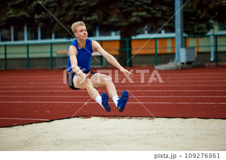 Precision and poise define athlete's descent into sand. Athletic man, professional sportsman sets new long jump record. 109276861