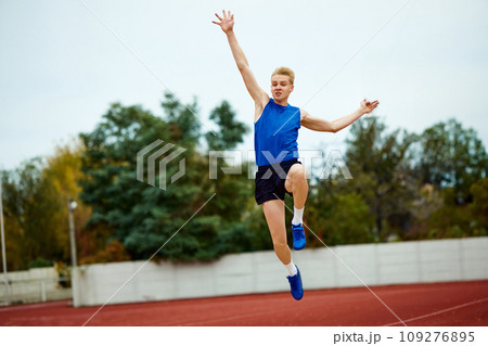 Runner's sprint culminating in long jump to sand. Competitive professional sportsman takeoff of grand for a precise sand-filled landing. Runner's sprint culminating in long jump to sand. Competitive professional sportsman takeoff of grand for a precise sand-filled landing. 109276895