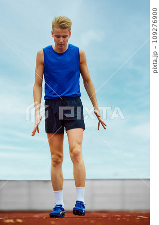 Focused runner propelling forward with intent. Young athlete man, professional sportsman warming-up before championship. 109276900