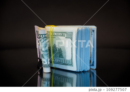 stack of dollar bills collected in an elastic band and a stationery clip 109277507