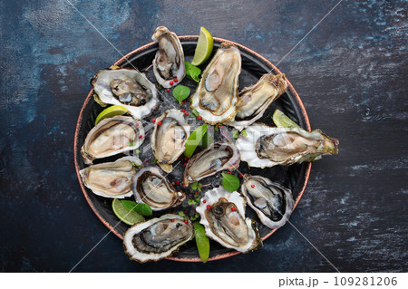 Fresh oysters with lime on round plate. Oyster in half shell. Flat lay. Top view. Copy space. 109281206