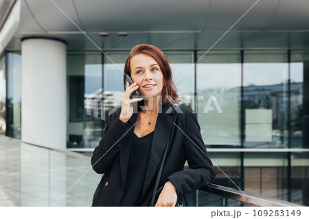 Middle aged businesswoman making a phone call while standing outdoors Middle aged businesswoman making a phone call while standing outdoors 109283149