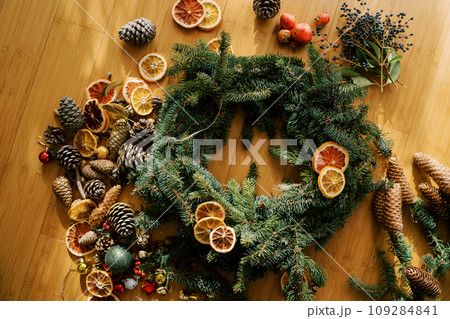 Pieces of dried fruits lie on a round frame of a Christmas wreath surrounded by accessories 109284841