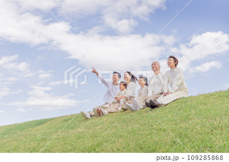 土手に座る3世代家族・三世代家族 109285868