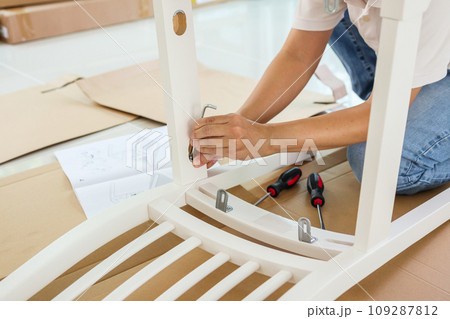Man assembling white chair furniture at home 109287812