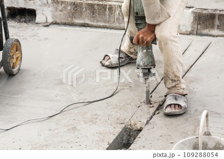 Construction worker using jackhammer drilling concrete surface Construction worker using jackhammer drilling concrete surface 109288054