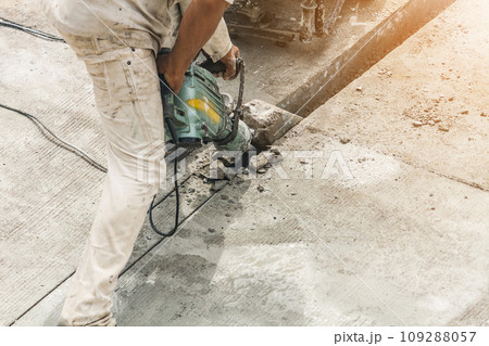 Construction worker using jackhammer drilling concrete surface Construction worker using jackhammer drilling concrete surface 109288057