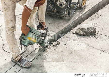 Construction worker using jackhammer drilling concrete surface 109288058