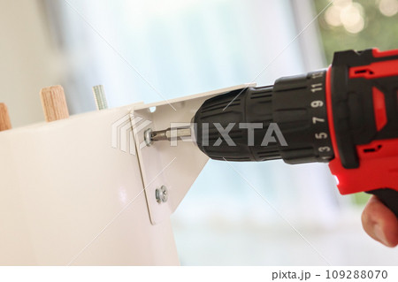 man assembling white table furniture at home using cordless screwdriver man assembling white table furniture at home using cordless screwdriver 109288070