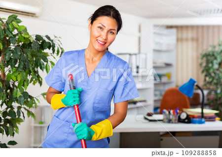 Woman wiping office floor with mop Woman wiping office floor with mop 109288858