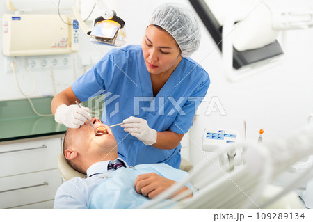 Focused woman dentist treats a man patient 109289134