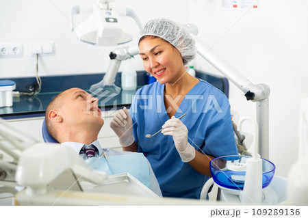 Dentist inspects male patient teeth 109289136
