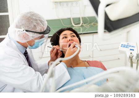 Dentist drilling tooth to asian female patient Dentist drilling tooth to asian female patient 109289163