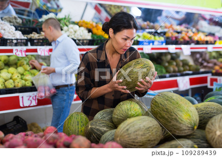 Female shopper choosing ripe melon on counter at farmers market 109289439