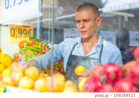 Supermarket worker setting out goods in greengrocer 109289521