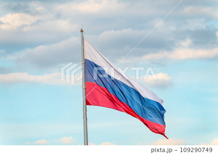 Russian tricolor flag waving in the wind against a blue sky. 109290749