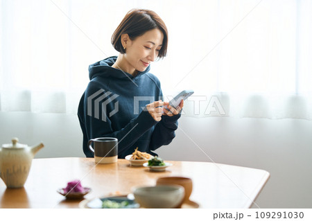 食事中にスマートフォンを手に取る女性 食事中にスマートフォンを手に取る女性 109291030