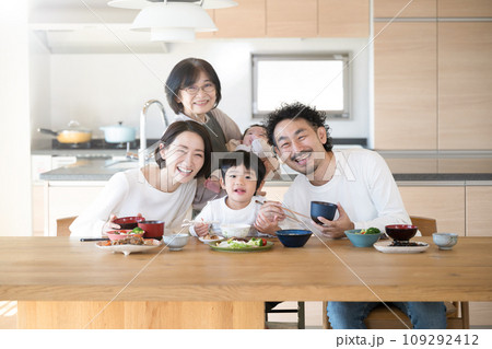 同居や二世帯住宅などのイメージ おばあちゃんと子どもたちと孫の三世代家族のダイニング カメラ目線 同居や二世帯住宅などのイメージ おばあちゃんと子どもたちと孫の三世代家族のダイニング カメラ目線 109292412