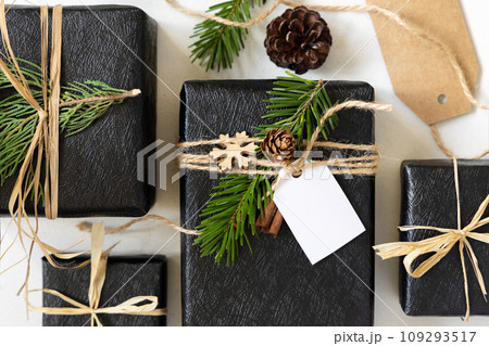 Black Christmas presents with blank gift tag, with fir branch and decorations, Mockup 109293517