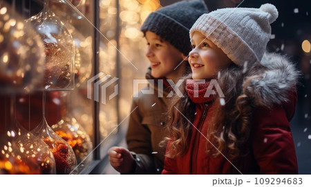 Two small children a boy and a girl on a snowy winter street are looking at a shop window 109294683