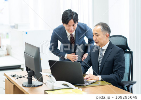オフィスで打ち合わせをする新入社員と管理職の男性のビジネスマン オフィスで打ち合わせをする新入社員と管理職の男性のビジネスマン 109295049