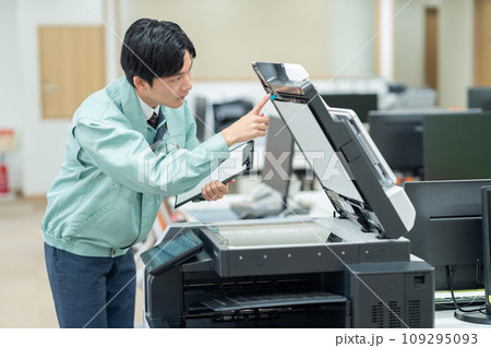 オフィスでコピー機をメンテナンスする若い男性の作業員 109295093