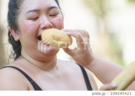 Cheerful two woman overweight in sportswear have fun and enjoy eating bread while exercising 109295421