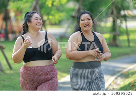 Cheerful two women overweight in sportswear have fun exercising in garden Cheerful two women overweight in sportswear have fun exercising in garden 109295625