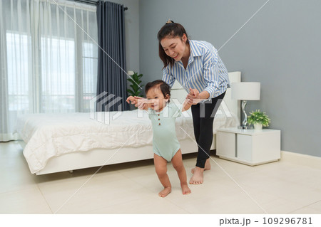 infant baby learn walking first step with mother holding hand helping infant baby learn walking first step with mother holding hand helping 109296781