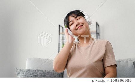 Young woman listening to music with headphone and relaxing while sitting on the sofa at home. Young woman listening to music with headphone and relaxing while sitting on the sofa at home. 109296989