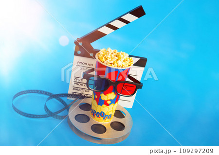 Movie clapper, pop corn, 3D glasses and film reel on blue background. Collage design Movie clapper, pop corn, 3D glasses and film reel on blue background. Collage design 109297209
