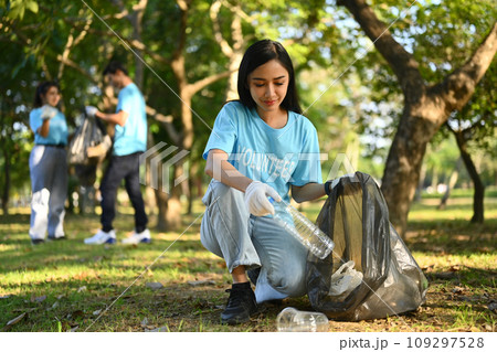 Beautiful young woman volunteer with team cleaning up the park. Environmental protection concept Beautiful young woman volunteer with team cleaning up the park. Environmental protection concept 109297528