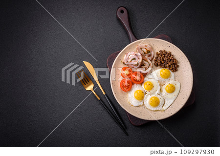 Delicious nutritious breakfast of fried quail eggs, bacon, legumes and cherry tomatoes 109297930
