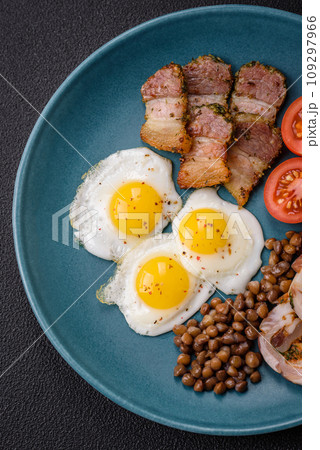 Delicious nutritious breakfast of fried quail eggs, bacon, legumes and cherry tomatoes 109297966