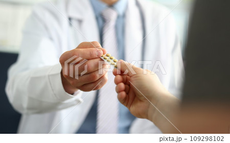 Closeup of doctor hand giving medical pills to patient 109298102