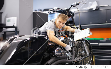 Male mechanic diagnoses modern motorcycle in service center Male mechanic diagnoses modern motorcycle in service center 109298247