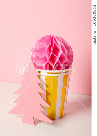 Paper cups, ball and Christmas tree on pink background 109300953