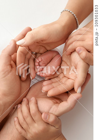Children's foot in the hands of mother, father, parents. Feet of a tiny newborn close up. Little baby legs. Mom and her child. Happy family concept. Beautiful concept image of motherhood stock photo.  109301033