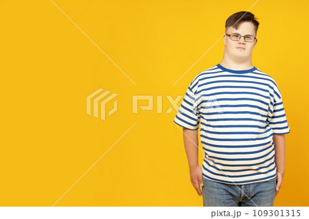 A boy with down syndrome in glasses on a yellow background 109301315