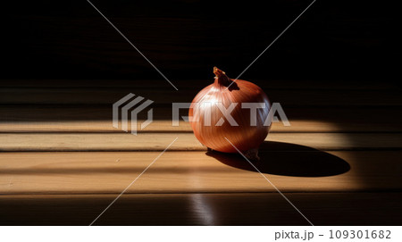 Lifestyle product shot of beautiful fresh onion highlighted by the sun on a wooden table. Play light and shadow Lifestyle product shot of beautiful fresh onion highlighted by the sun on a wooden table. Play light and shadow 109301682
