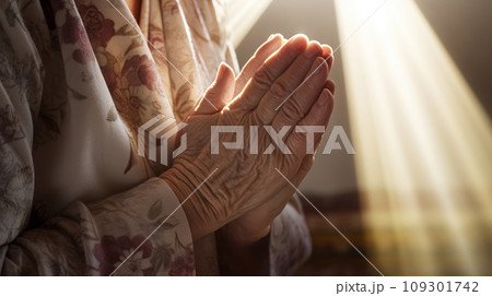 Lifestyle closeup shot of grandma prays with folded hands under the sun light. Play of light and shadow 109301742