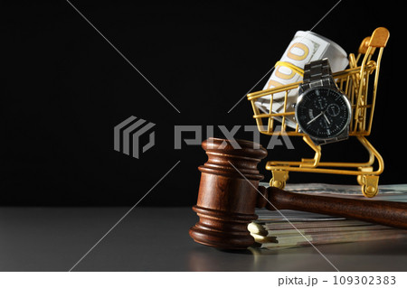 Clock and money in shopping cart, wooden gavel on black background, space for text Clock and money in shopping cart, wooden gavel on black background, space for text 109302383