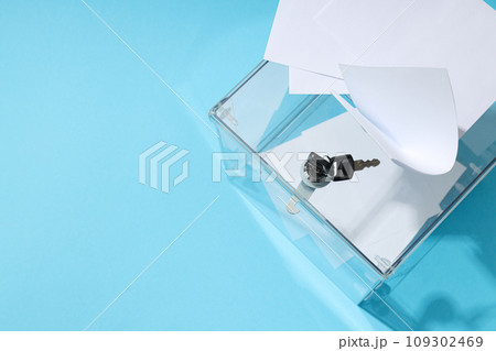 Voting box with papers and key on blue background, space for text 109302469
